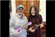 Two women in jeans play a purple ukulele and a brown ukulele.