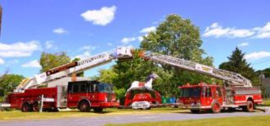 The ladders of two parked fire engines meet to form a kind of arch.